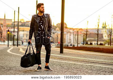 A handsome young hipster man standing next to a tramline and looking around