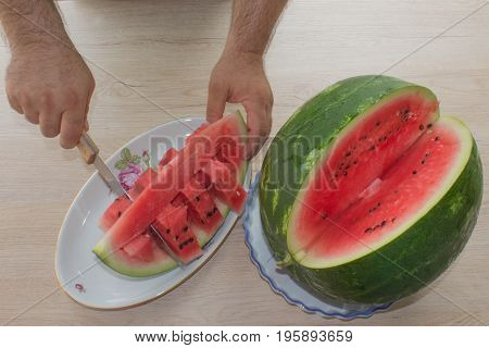 Men hand hold from on fresh watermelon cutting for eatin on table background. Male cutting a delicious sweet watermelon