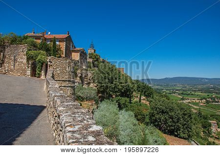 Panoramic view of street, house and hills of Provence under sunny blue sky, at the village of Ménerbes. Located in the Vaucluse department, Provence-Alpes-Côte d'Azur region, southeastern France