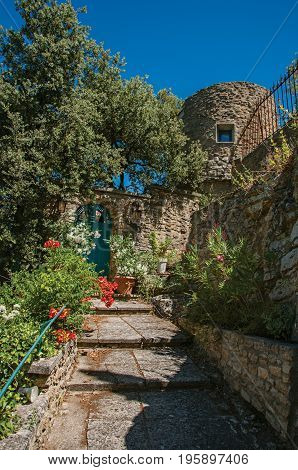 View of staircase and gate with flowers and sunny blue sky in the background, at the village of Ménerbes. Located in the Vaucluse department, Provence-Alpes-Côte d'Azur region, southeastern France