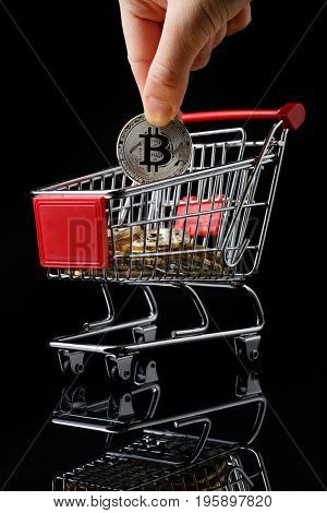 hand throws a bitcoin into trolley.