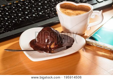 Cup Of Coffee And Chocolate Cake Next To Computer.