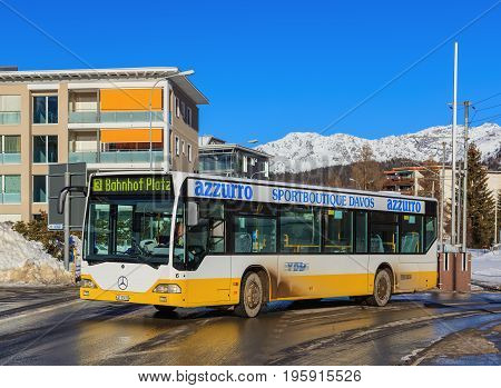 Davos, Switzerland - 26 January, 2017: a bus passing along a street in the town of Davos, mountains in the background. Davos is an alpine town in the Swiss canton of Graubunden, known for the annual World Economic Forum taking place there.