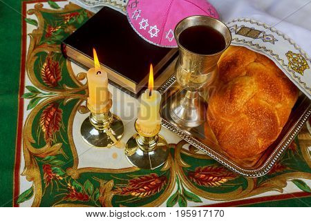 Shabbat Candles In Glass Candlesticks With Blurred Covered Challah Background.