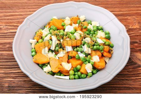 Warm salad with roasted pumpkin, peas and cheese brie. Low fat healthy eating concept.