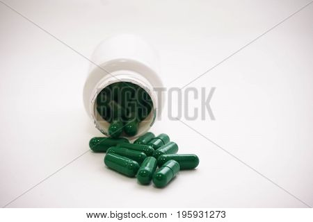 Medicine green  pills or capsules and bottle on white background with copy space.