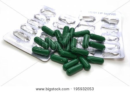 Medicine green  pills or capsules and aluminum foil blister on  white background with copy space.  treatment medication