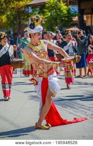 CHIANGMAI THAILAND - JANUARY 25 2015: Dancer man with traditional costume holding tray with pedestal of flower dancing in parade of 22nd Traditional Skirt Fabric and The Indigenous Product and Culture Festival in Mae Chaem Chiangmai Thailand