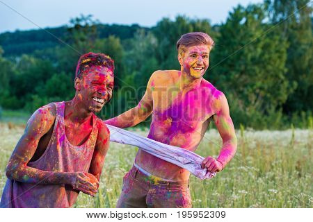 portrait of happy muticultural men with colorful paint on bodies at holi festival