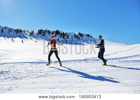 Cheerful young couple having fun in winter park.