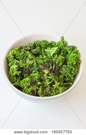 Oily kale chips in big bowl on white background. Kale salad. Organic food