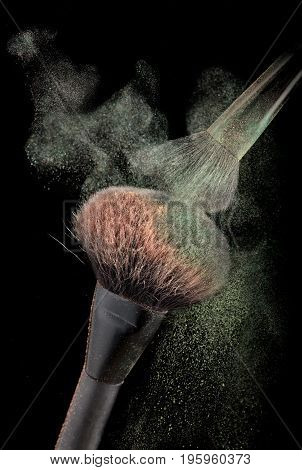 Powderbrushes with explosion of colorful powder on black background.Motion blur.
