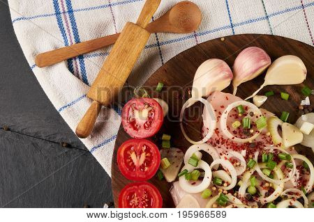Fresh chicken meat with herb and fresh vegetables with spices seasoning on wooden board on black stone background. Rustic style. Healthy low-calories diet food. Top view close-up.
