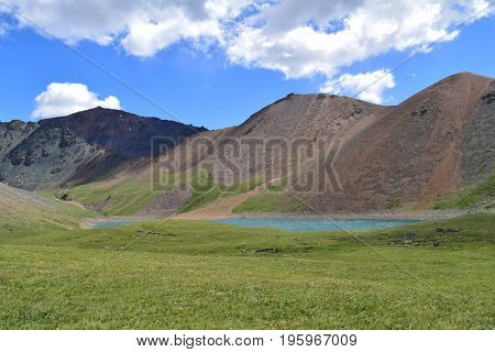 Hills green meadow and lake in Altai mountains. Altay Republic Siberia Russia.