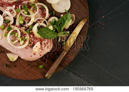 Raw food grocery full of proteins on wooden brown cutting rustic board on black stone background. Chicken fillet onion herbs. Healthy sport diet background. Healthcare lifestyle or proteins concept