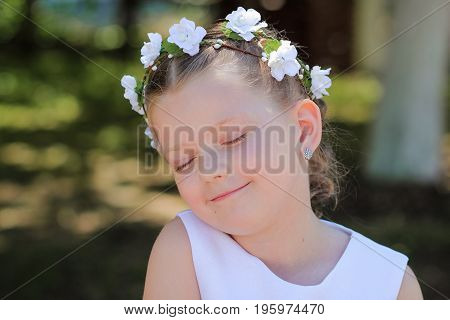 Little girl dreaming with eyes closed child with a wreath of artificial flowers on her head