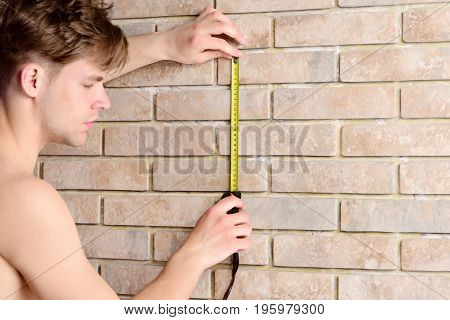 Guy Measures Brick Wall With Builders Ruler. Worker With Roulette