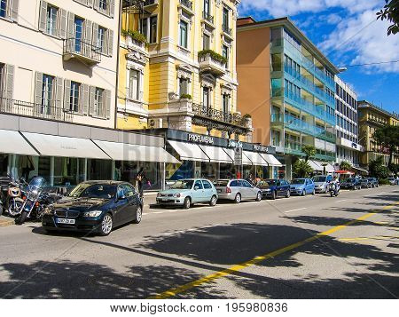 Lugano Switzerland - August 10 2007: Downtown city with old Italian architecture and Profumeria building with sign street and cars during sunny summer day