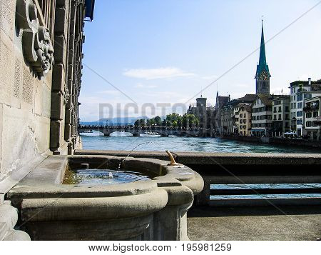Zurich, Switzerland - August 11, 2007: Water Fountain With River, Bridges And Cityscape During Summe
