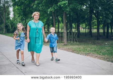 Grandmother playing in the park with grandchildren, siter with brother