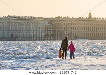 Mom Ang Child In Bright Clothes Walking On The Ice Of Frozen Neva In Sunny Winter Day, Hermitage On 