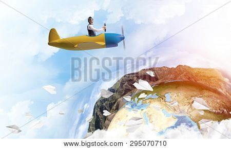 Pilot In Leather Helmet Driving Propeller Plane On Background Of Blue Cloudy Sky. Traveling Around T