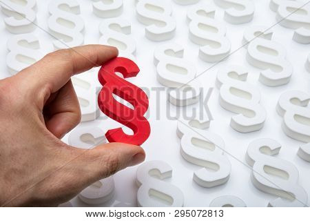 Person's Hand Holding Red Paragraph Sign
