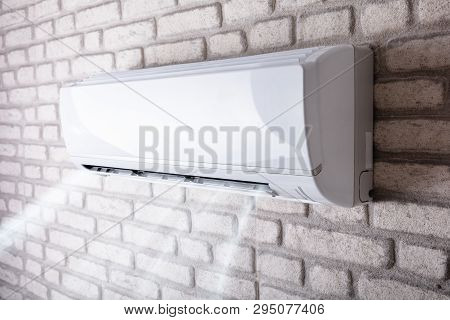 White Air Conditioner Blowing Cold Air On Brick Wall In Living Room