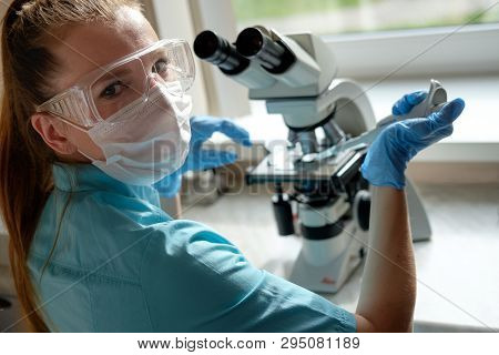 Woman Laborant Working With Microscope Holding Automatic Pipette
