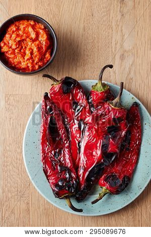 Roasted red peppers on a plate with bowl of ajvar