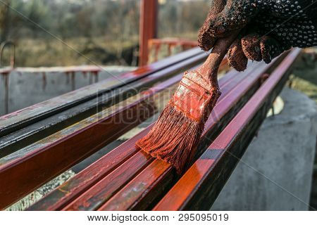 House Painter Paints Metal Structures. Protective Coating Of Steel Closed Profiles With Primer Iron 