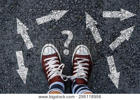 Man In Shoes Standing On Asphalt Next To Multitude Of Arrows In Different Directions And Question Ma