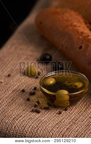 Fresh Bread Baguette With Olive Oil, Olives. Cheese And Rosemary On Wooden Background. Teasty Breakf