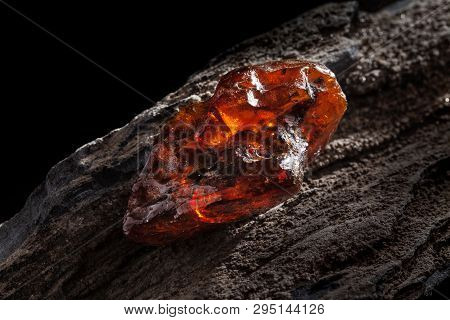 Natural Amber. A Piece Of Yellow And Red Semi Transparent Natural Amber On Piece Of Stoned Wood.