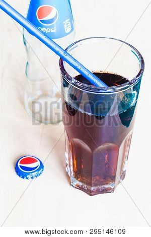 Moscow, Russia - April 4, 2019: Pepsi Beverage In Glass With Blue Drinking Straw, Used Crown Cap And