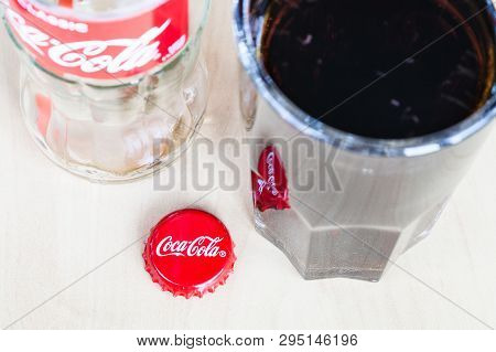 Moscow, Russia - April 4, 2019: Crown Cap Near Glass With Drink And Empty Bottle Of Coca-cola Bevera