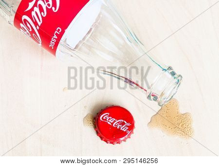 Moscow, Russia - April 4, 2019: Red Crown Cap, Empty Bottle From Coca-cola Beverage And Spilled Pudd