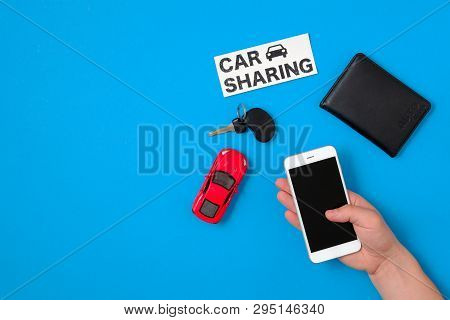 Car Sharing App Concept. Toy Car, Car Key, Auto Drive License, Human Hand With Smartphone And Text S