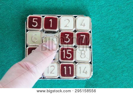 Finger Slides Tile In 15-puzzle (magic 15) Sliding Puzzle Game Close Up On Green Baize Table