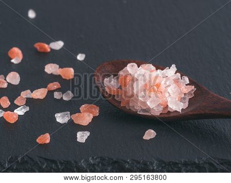 Himalayan Pink Salt In Spoon On Black Stone Background. Copy Space