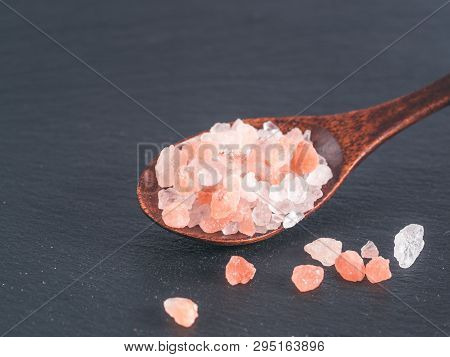 Himalayan Pink Salt In Spoon On Black Stone Background. Copy Space