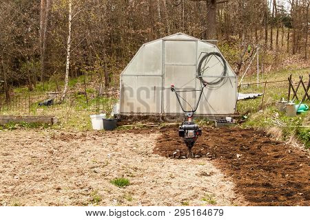 Spring Preparation Soil For Seeding With Tiller. Spring Work In The Garden. Farmer Plows The Land Wi