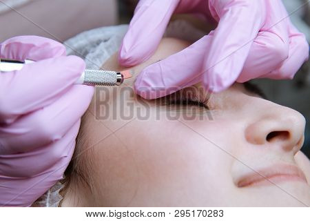 Permanent Makeup For Eyebrows. Microblading Brow. Beautician Doing Eyebrow Tattooing For Female Face