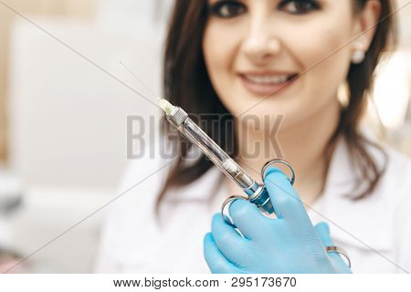 Closeup Photo Of Female Dentist In The Dental Room Holding Oral Syringe.