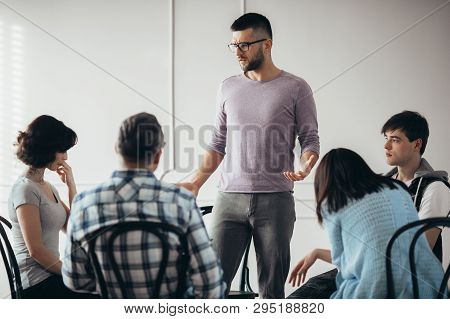 Young Sad Man Talking To The Group Of People During Psychotherapy