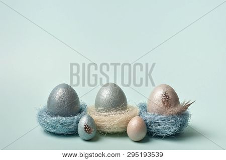 Easter, Silver, Blue Eggs On A Blue  Background. Decorated With Feathers.  In The Nest Of Sisal Fibr