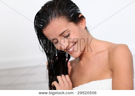 Acondicionador del pelo aplicando hermosa mujer