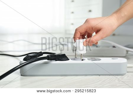 Woman Inserting Power Plug Into Extension Cord On Floor Indoors, Closeup With Space For Text. Electr