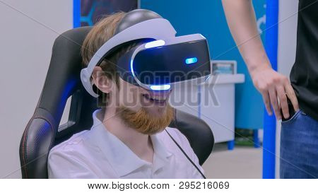 Young Man Smiling And Using Virtual Reality Headset At Technology Exhibition. Future And Video Game 