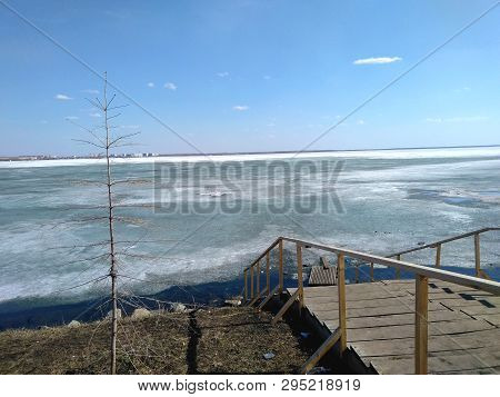 Wooden Stairs Down To The Lake Shore In The Spring, Background, Horizon Blue Sky Clouds Tree